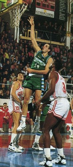 the basketball player is trying to block the ball from going into the basket as others watch