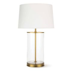 a clear glass table lamp with a gold base and a white shade on the top