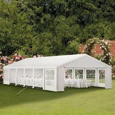 a large white tent with tables and chairs set up in front of some pink flowers