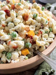 a wooden bowl filled with pasta salad on top of a table