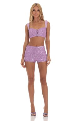 a woman wearing purple shorts and a crop top with sequins on the bottom