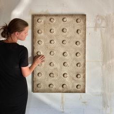 a woman standing in front of a wall with holes on it