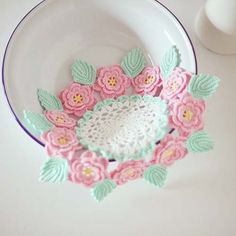 crocheted doily in a bowl with pink and green flowers on the rim
