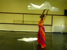 a woman in an orange and blue dress is holding a white sheet over her head