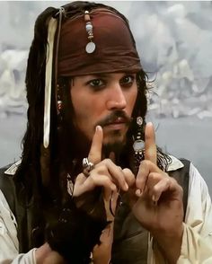 a man dressed as captain jack sparrow holding two fingers up to the side with one hand