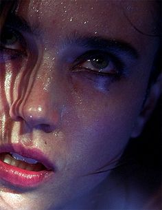 a close up of a woman's face with water all over her body and eyes