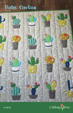 a quilted wall hanging with cactus and succulents in potted plants