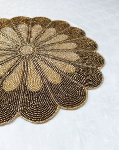 a close up of a doily on a white table cloth with brown and tan beads