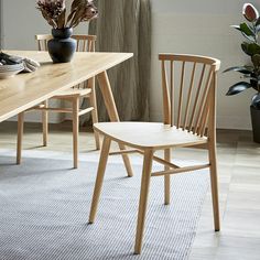 two wooden chairs sitting next to each other on top of a rug in front of a table