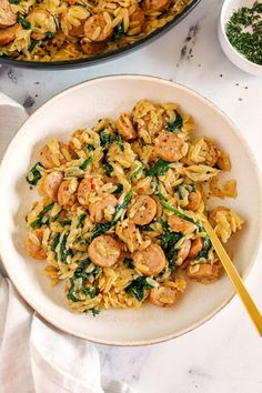 pasta with shrimp and spinach in a white bowl next to a skillet filled with pesto