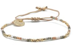 a bracelet with two beads and a gold disc on the clasp, sitting against a white background