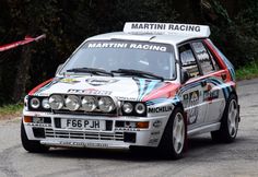 a rally car driving down a road with trees in the background