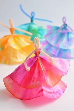 three colorful paper bags are sitting on a white surface, with string attached to them