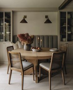 a dining room table with chairs around it and flowers on the table in vases