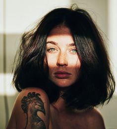 a woman with a tattoo on her arm posing for a photo in front of a mirror