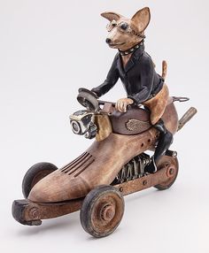 a statue of a dog riding on top of a motorbike with a helmet and goggles