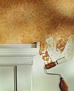 a person is painting the ceiling in their kitchen with brown and white paint on it