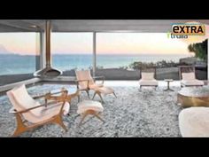 a living room filled with lots of furniture next to a large window overlooking the ocean