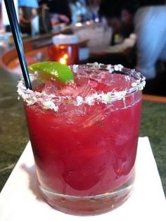 a close up of a drink on a table with a green garnish in it