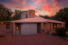 a small house with a round roof and a pink sunset in the sky behind it