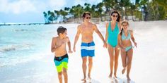 a family walking on the beach in front of some palm trees and blue water with white sand