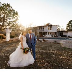 a bride and groom are standing in front of a large house with a swimming pool