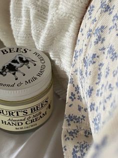 a close up of a jar of butter on a bed with a white and blue blanket