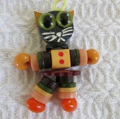 a cat ornament made out of glass beads on a white surface with an orange and green stripe