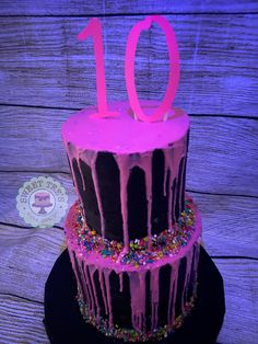 a birthday cake with pink icing and sprinkles on the top tier