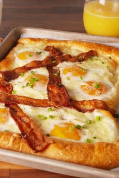 an egg and bacon pizza in a pan on a table