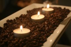 coffee beans and lit candles are arranged in a rectangle on top of the table