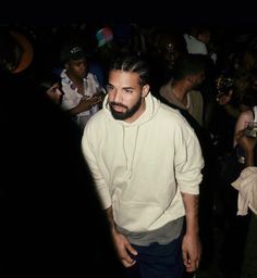 a man standing in front of a crowd at a party wearing a white hoodie