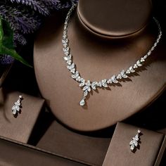 a necklace and earring set on display next to purple flowers