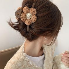 a close up of a person wearing a hair clip with flowers in the middle of their hair