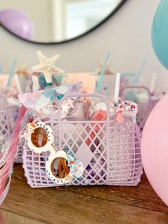 a table topped with baskets filled with lots of candy next to pink and blue balloons