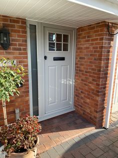 a white front door on a brick house with potted plants in the foreground