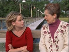 two women are sitting on a bench and one is looking at the other woman's face