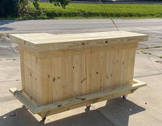 a large wooden box sitting on top of a sidewalk next to a street and grass