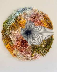 an umbrella made out of flowers and leaves on a white surface with no one around it