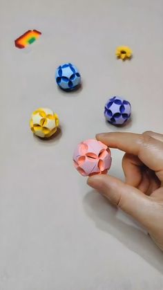 someone is holding some origami balls in their hand and they are all different colors
