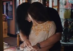 a man and woman standing next to each other in front of a counter with food on it