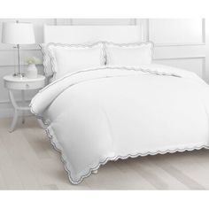 a white bed with scalloped edges and pillows