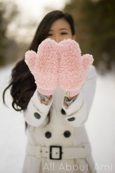 a woman in white coat holding up pink mitts
