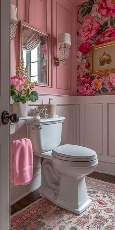 a white toilet sitting in a bathroom next to a pink flowered wallpaper and mirror