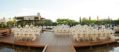 an outdoor wedding setup is set up on a wooden deck overlooking the water and trees