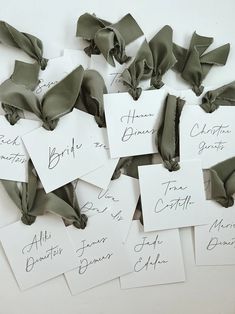 several pieces of paper with names and ribbons tied to them, all on top of each other