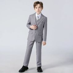 a young boy in a suit and tie posing for the camera with his hands on his hips