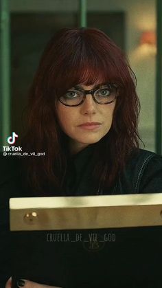 a woman with red hair and glasses looking at the camera