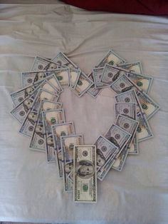 a heart made out of money sitting on top of a white sheet covered in paper