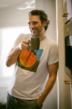 a man holding a coffee cup in his right hand and looking at the camera with an excited look on his face